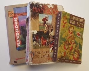 3 Boy Scouts of America handbooks for various decades, each worn from use.