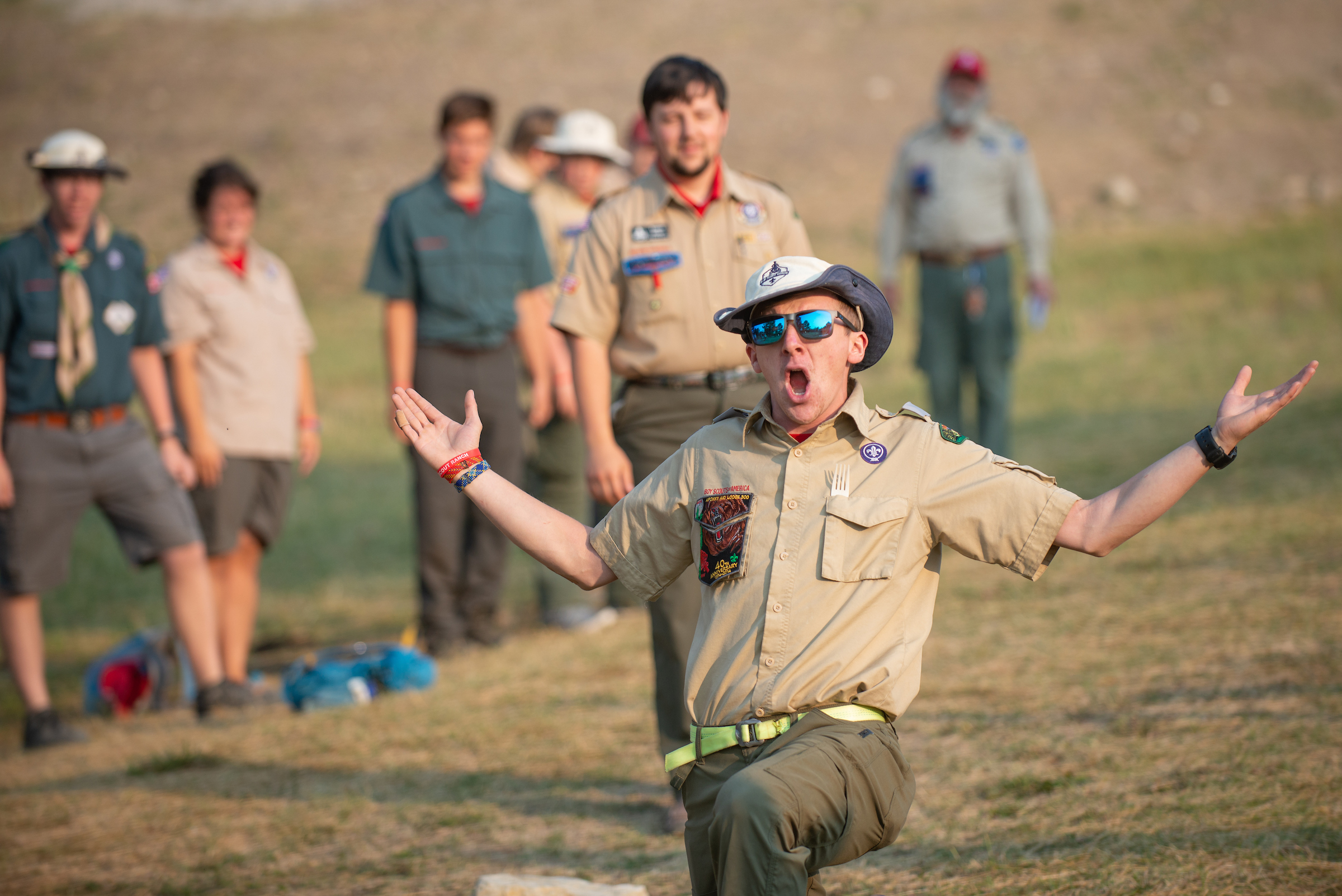 Boy Scouts camp counselor speaks enthusiastically to a group at summer camp