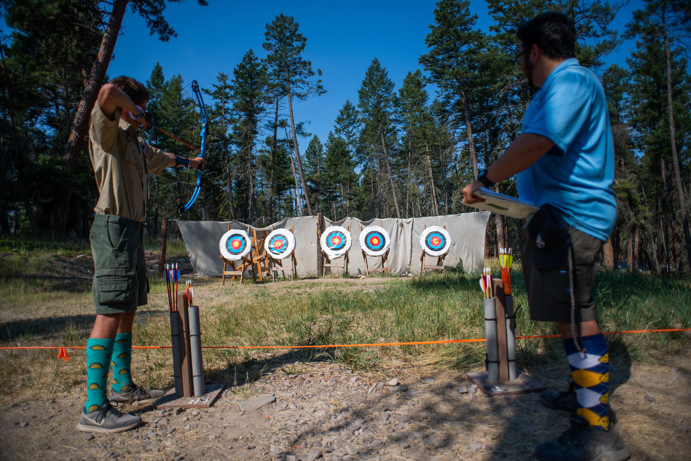 Camp counselor teaches Boy Scout archery at summer camp